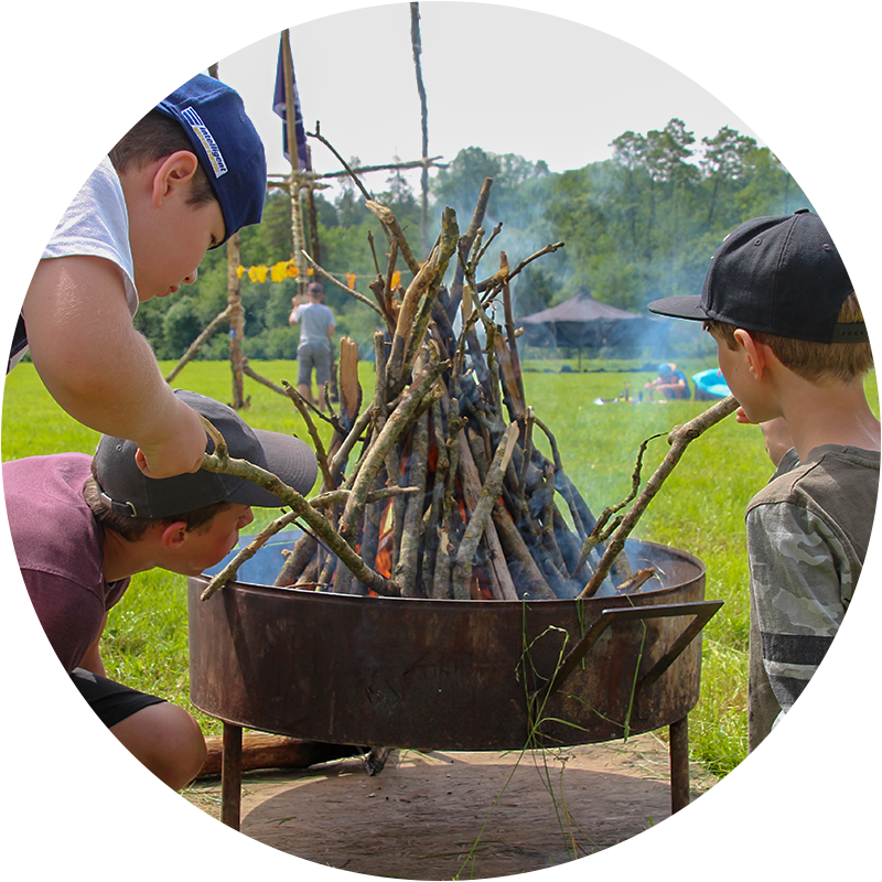 Pfingstlager im Pfadfinderstamm Galileo Galilei. Drei Kinder machen Feuer.